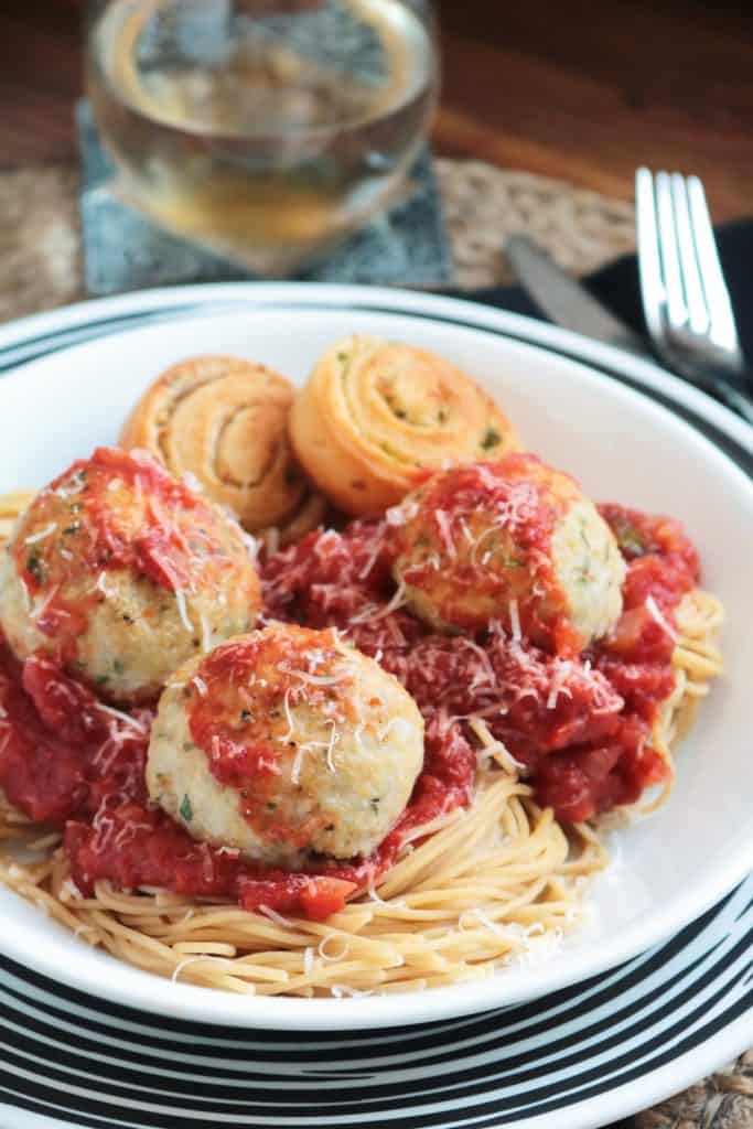 Baked Chicken Parmesan Meatballs served over spaghetti.
