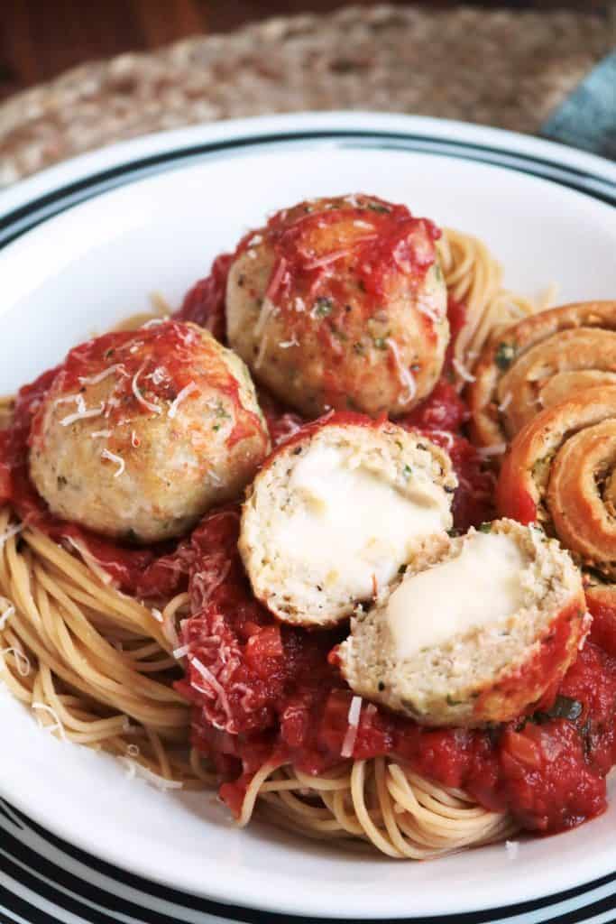 Baked Chicken Parmesan Meatballs in a bowl with spaghetti.