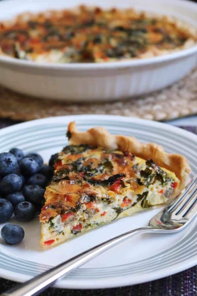 Kale Quiche - slice on a plate with blueberries.