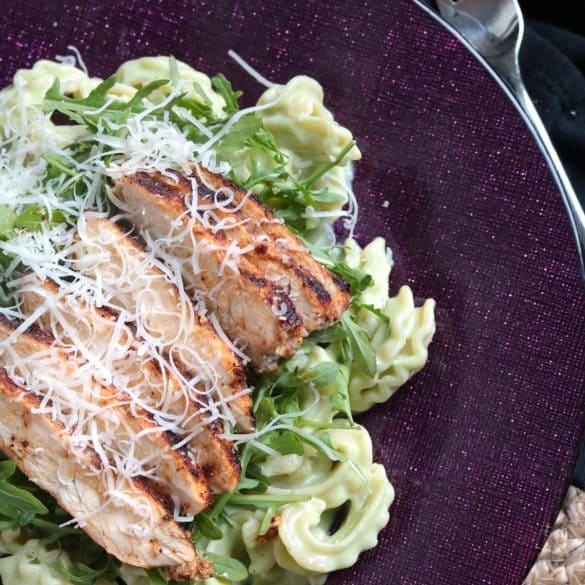 Lighter Avocado Alfredo Pasta served with Spicy Chicken and arugula on top.
