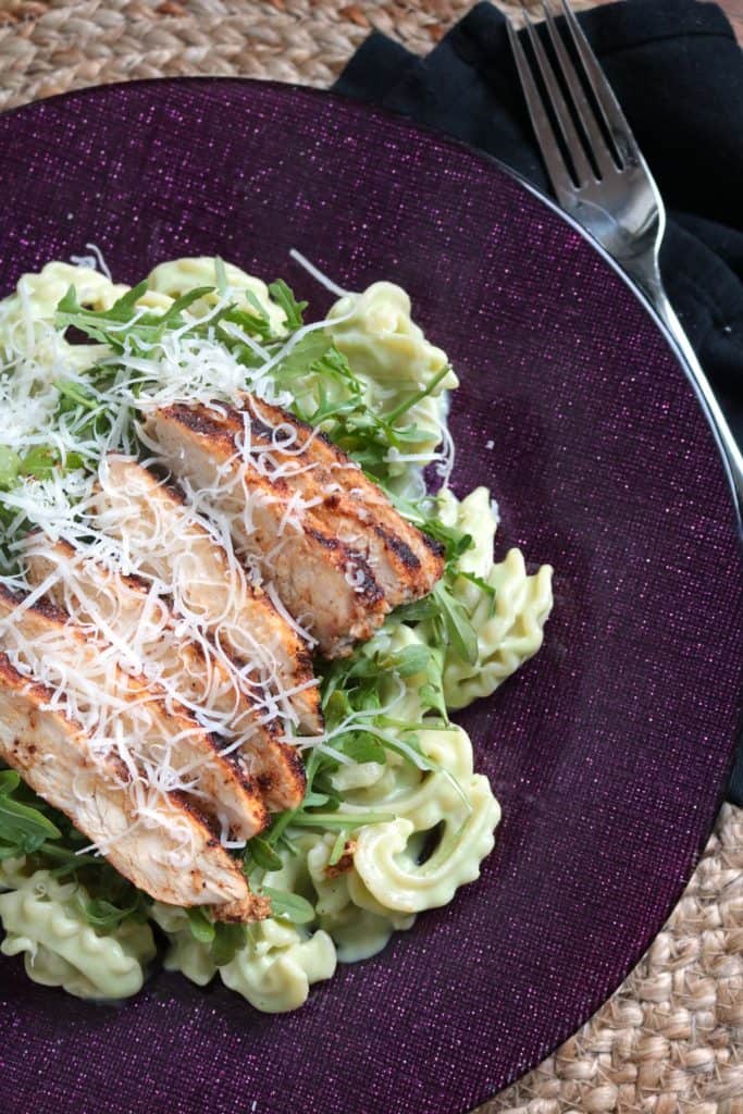 Lighter Avocado Alfredo Pasta served with Spicy Chicken and arugula on top.