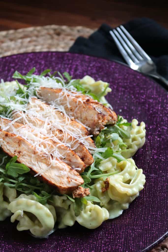 Lighter Avocado Alfredo Pasta with Spicy Chicken garnished with Parmesan cheese.
