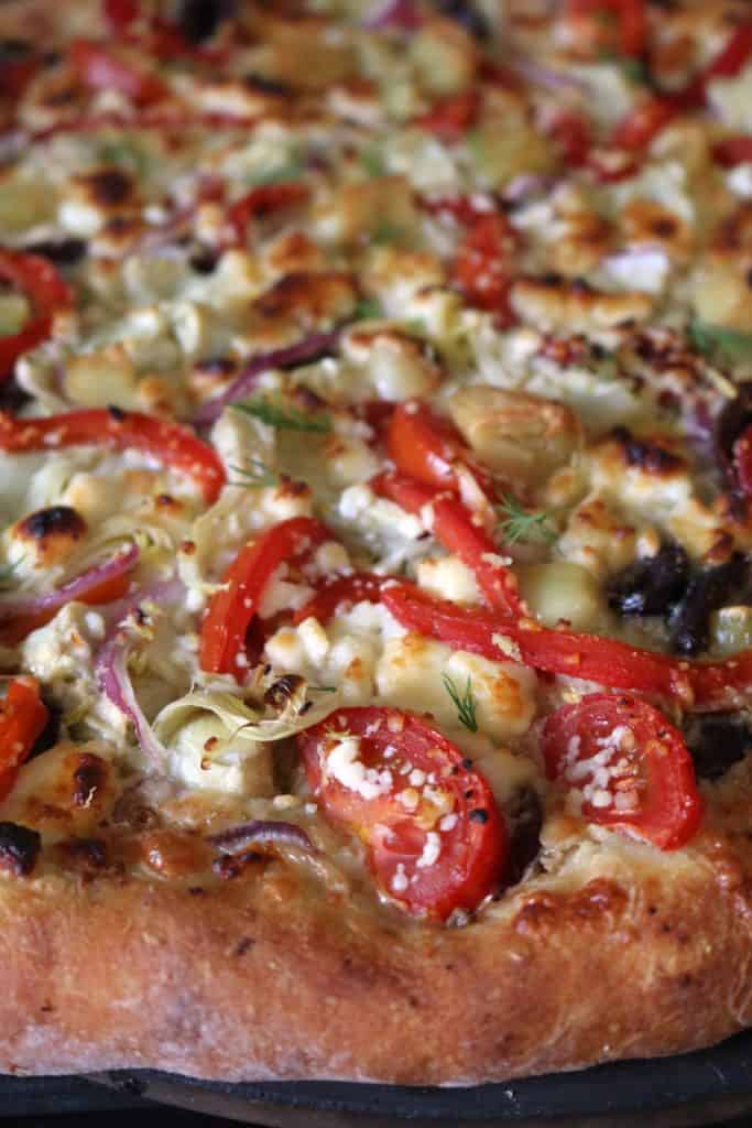Greek Pizza topped with Mozzarella, Feta, Roasted Red Peppers, Tomato, Artichoke Hearts, Olives, Roasted Garlic.