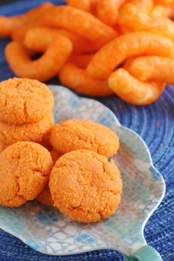 Cheetos Cookies on a plate with puffed Cheetos in the background.