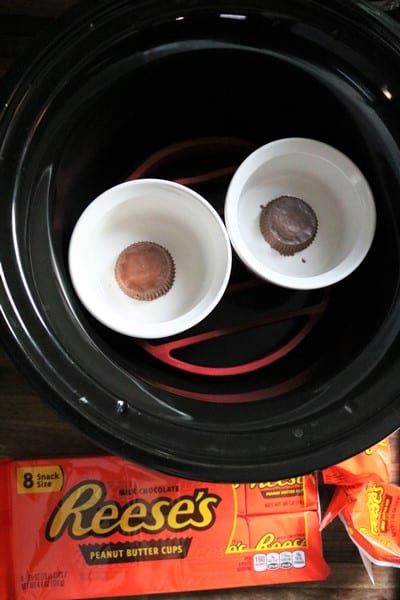 Ramekins with peanut butter cups in a slow cooker