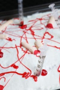 Bloody Poke Cake Topped with Candy Fingers and Syringes.