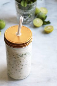 Frozen Coconut Mojitos in a glass with lid and straw.