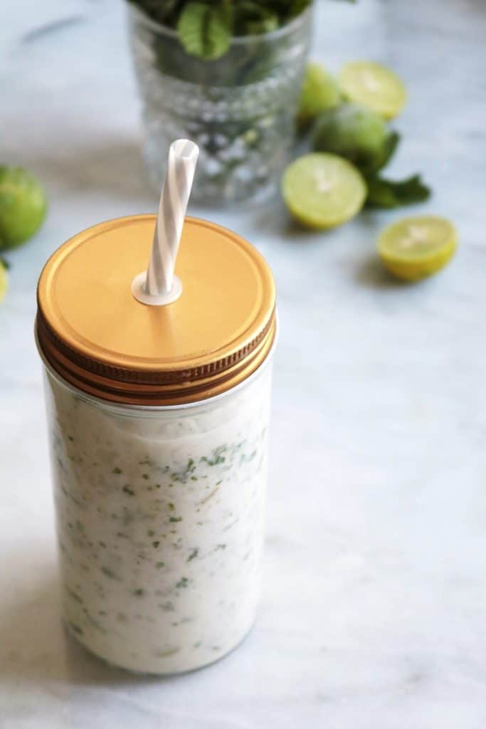 Frozen Coconut Mojitos in a glass with lid and straw.