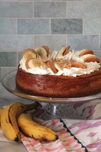 Banana Pudding Cheesecake, on a cake stand with whole bananas underneath.